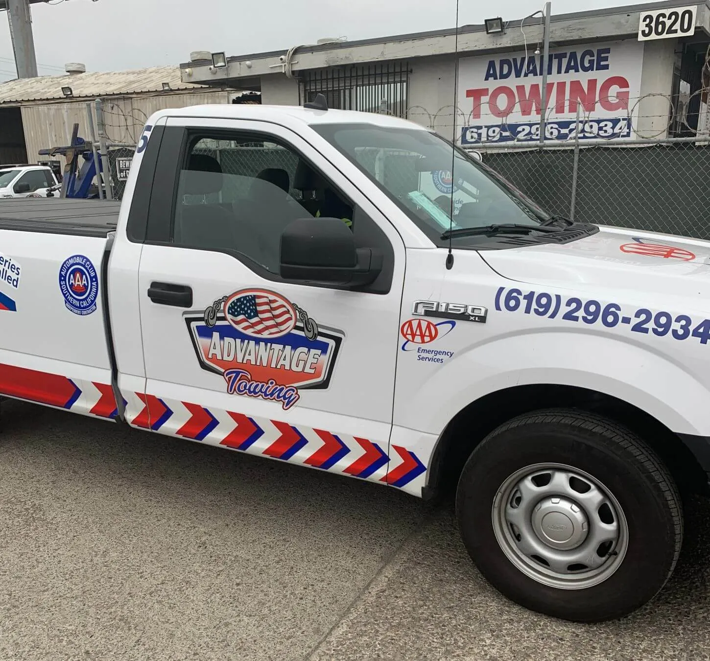 Roadside service pickup parked in front of the Advantage Towing yard sign