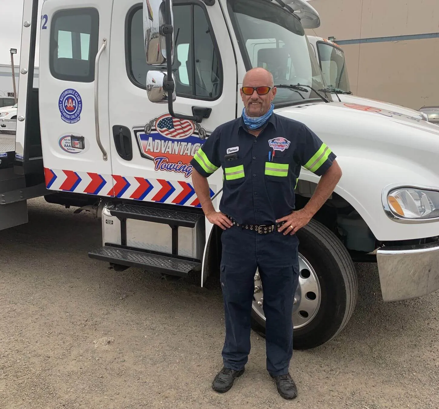 Advantage Towing operator in uniform standing in front of a rollback